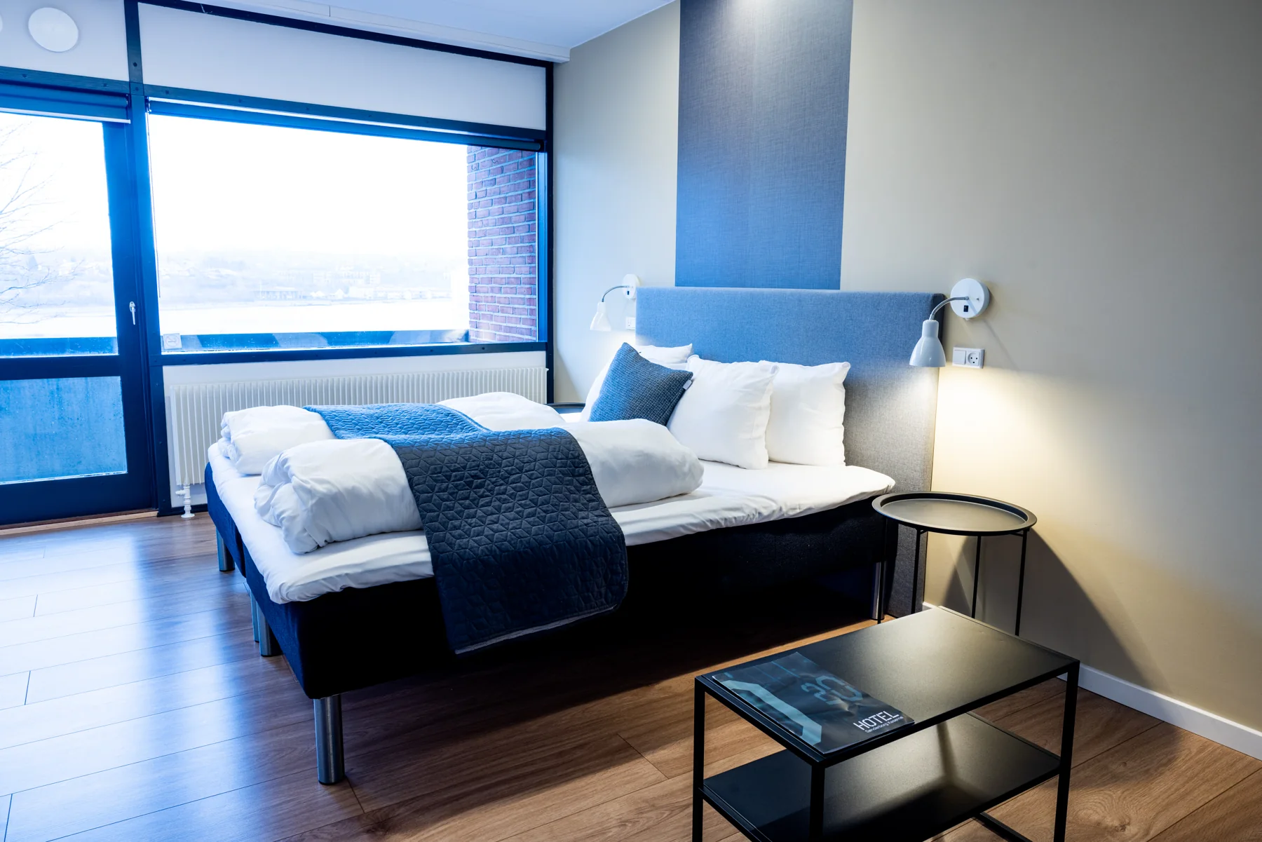 Lyst hotelværelse med dobbeltseng og balkon mod Alssund